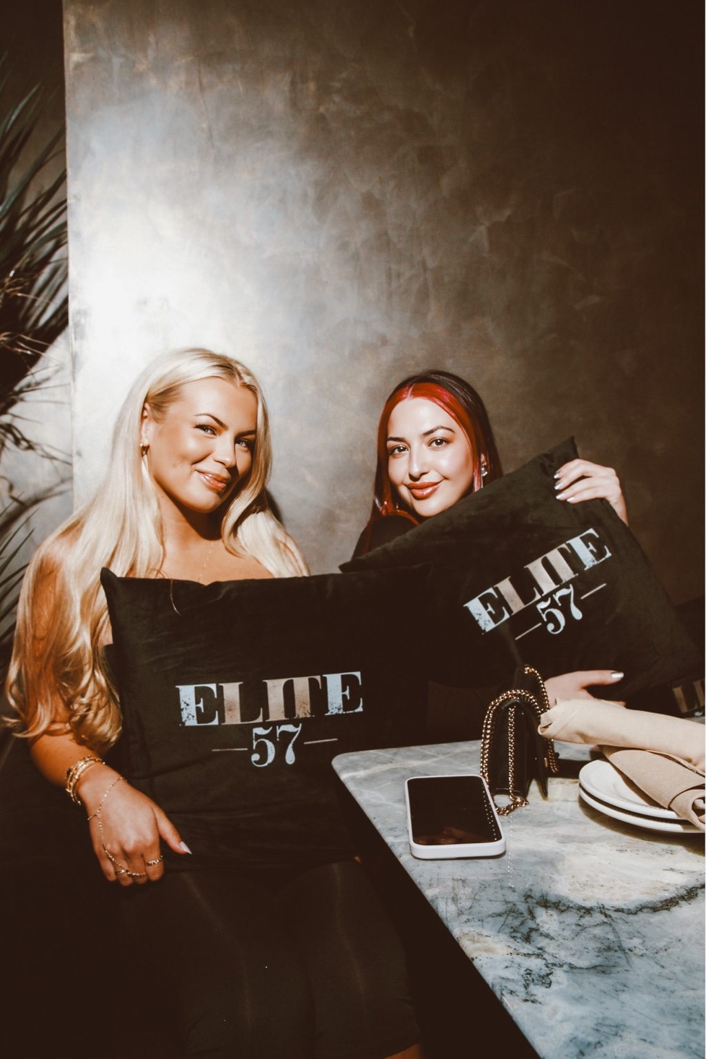 Two guests holding Elite 57 pillows at a marble table