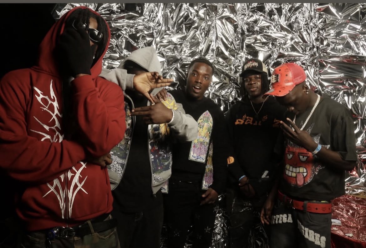 Crew photographed against a crumpled silver foil backdrop at a music video shoot