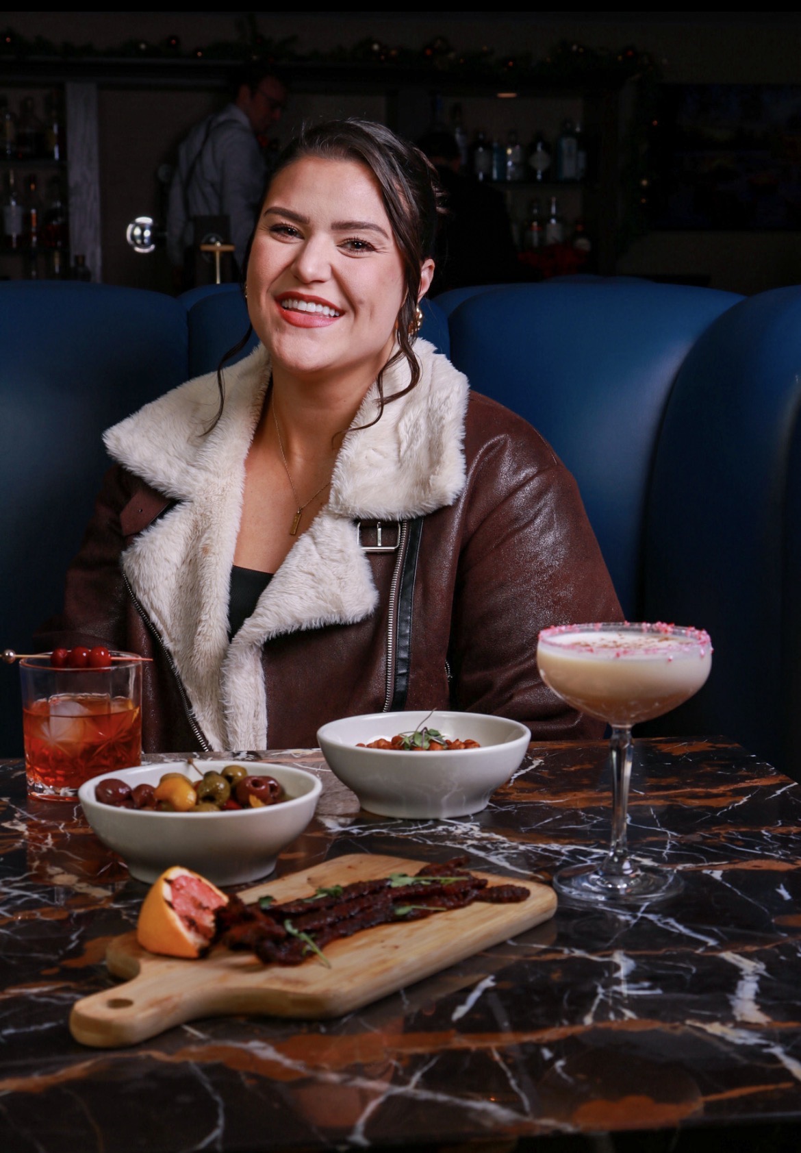 Guest photographed at a marble restaurant table with cocktails