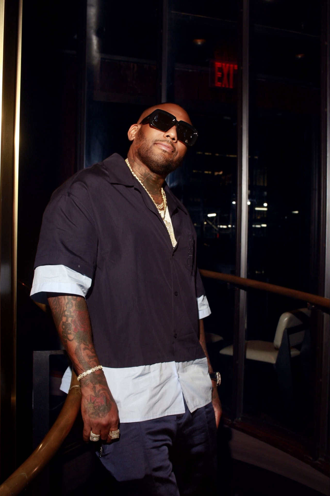 Guest in dark clothing and sunglasses photographed at an evening event