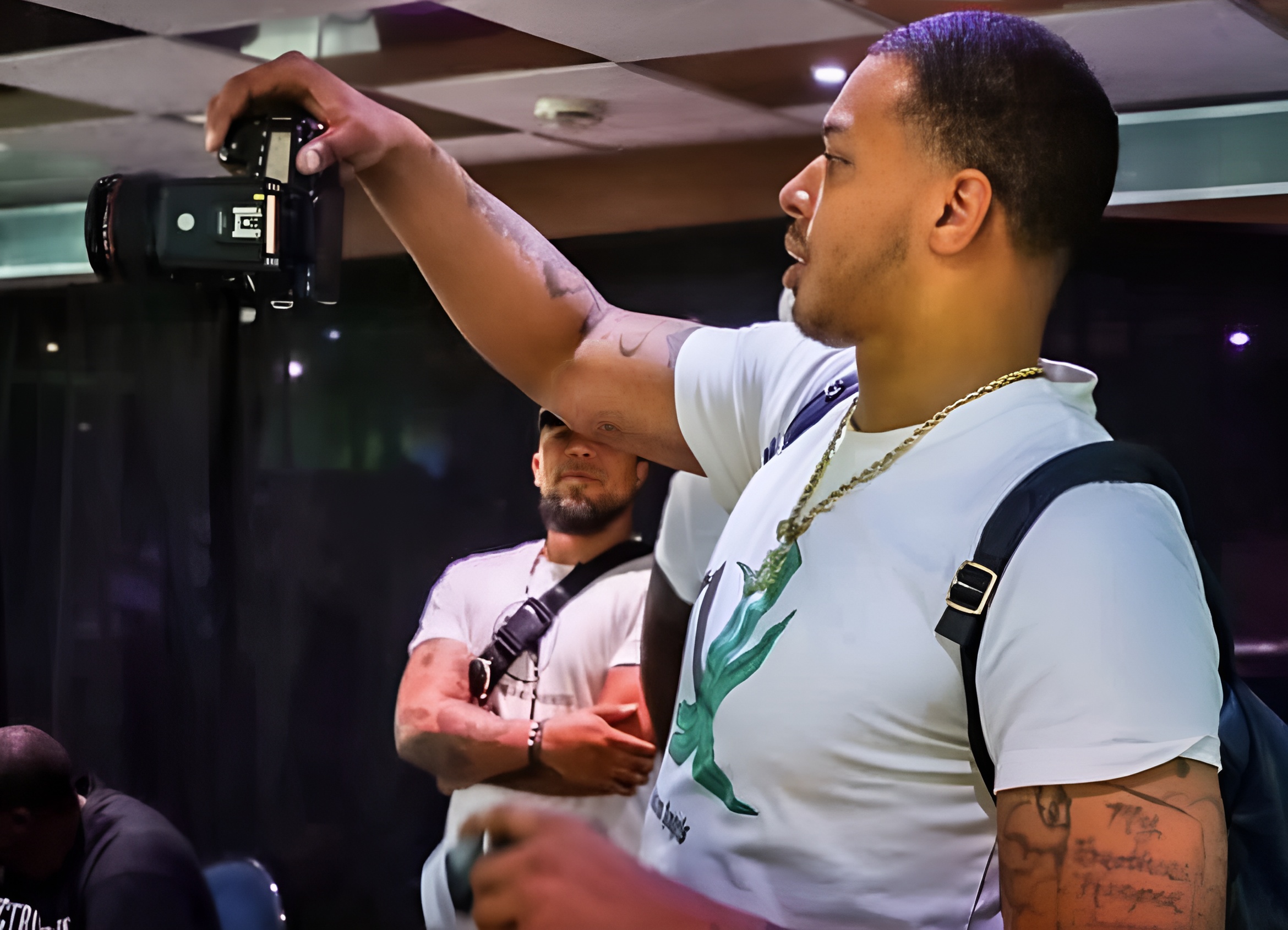 Vante photographing an event, camera raised above the room