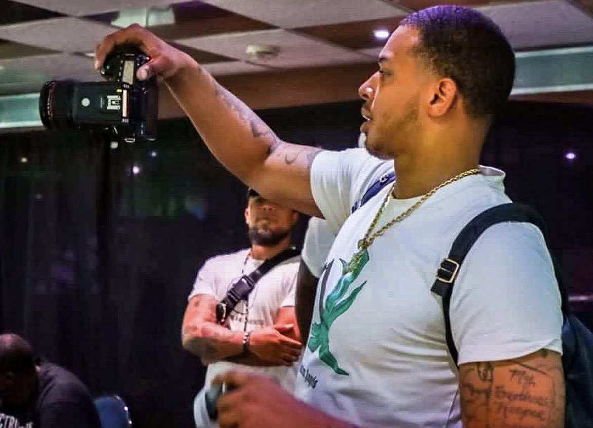 Vante photographing an event, camera raised above the room