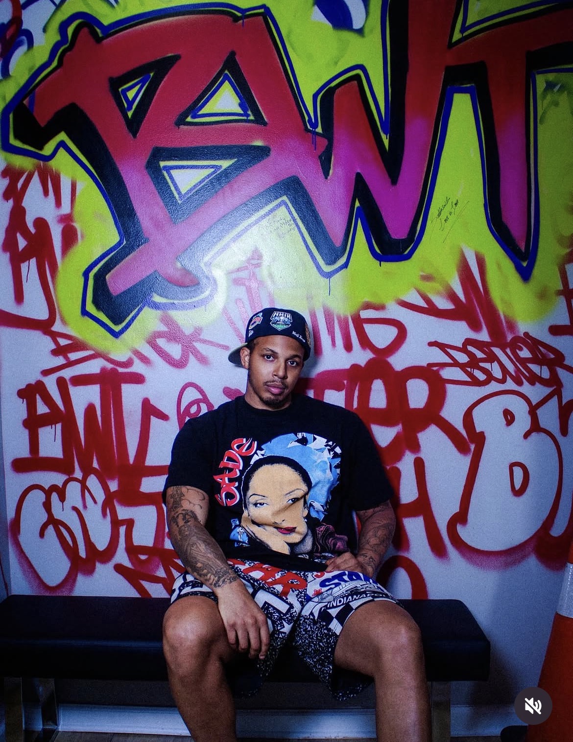 Vante photographed seated in front of a graffiti wall