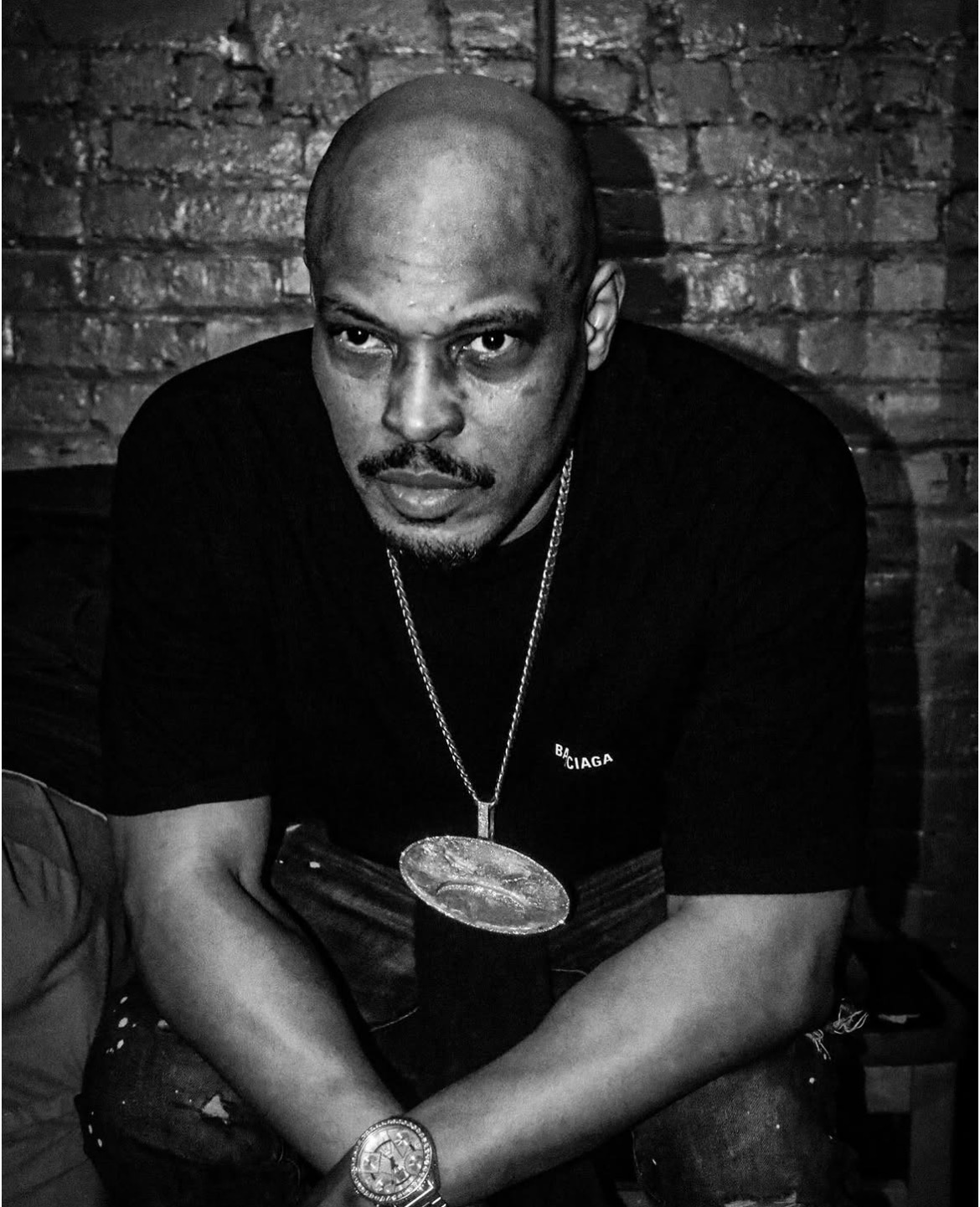 Black and white portrait against an exposed brick wall
